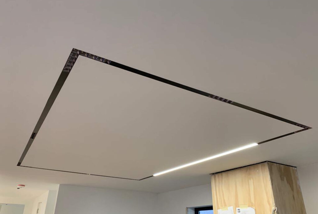 Lifestyle Construction Ceiling with a rectangular recessed light fixture, partially illuminated, in a modern interior space from a recent Toronto Renovation. Home Renovation In The GTA