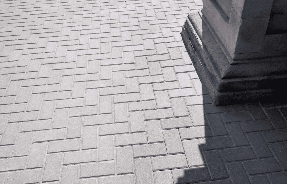 Lifestyle Construction A shadow cast by a building partially covers a paved ground with a herringbone brick pattern, reflecting the meticulous craftsmanship seen in Toronto Renovation projects. Home Renovation In The GTA