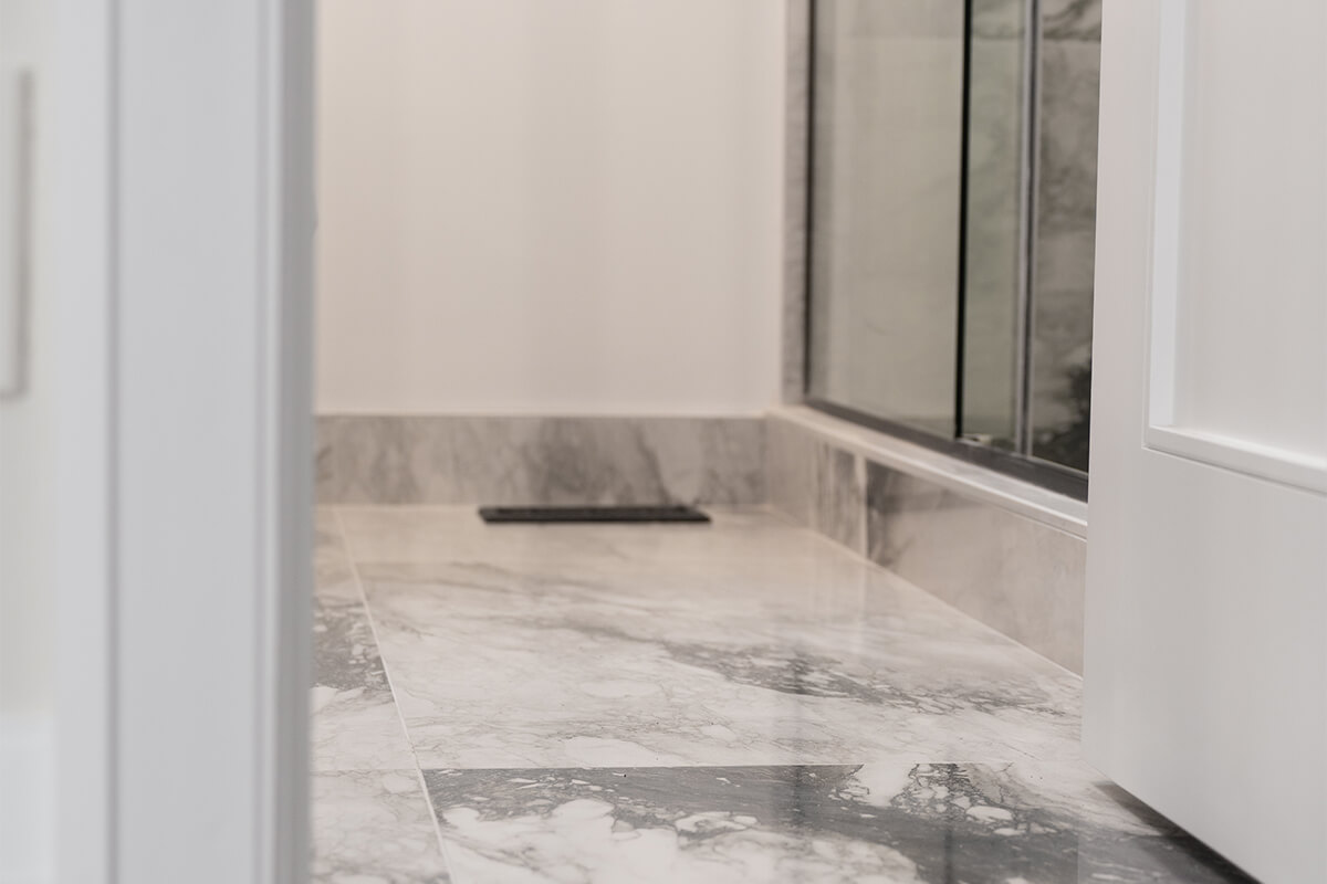 Lifestyle Construction A marble-tiled bathroom floor next to a glass shower door, a hallmark of elegant Toronto Renovation projects. Home Renovation In The GTA