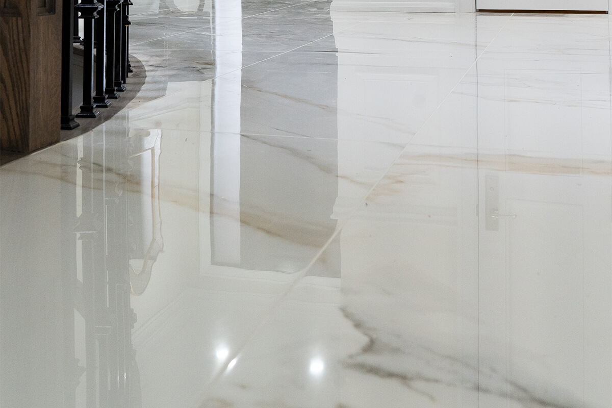 Lifestyle Construction A polished marble floor with a smooth, reflective surface graces this Toronto Renovation. The light-colored floor features subtle veining, enhancing the elegant look. Part of a staircase railing on the left is also visible, showcasing the meticulous craftsmanship typical of Lifestyle Construction projects. Home Renovation In The GTA