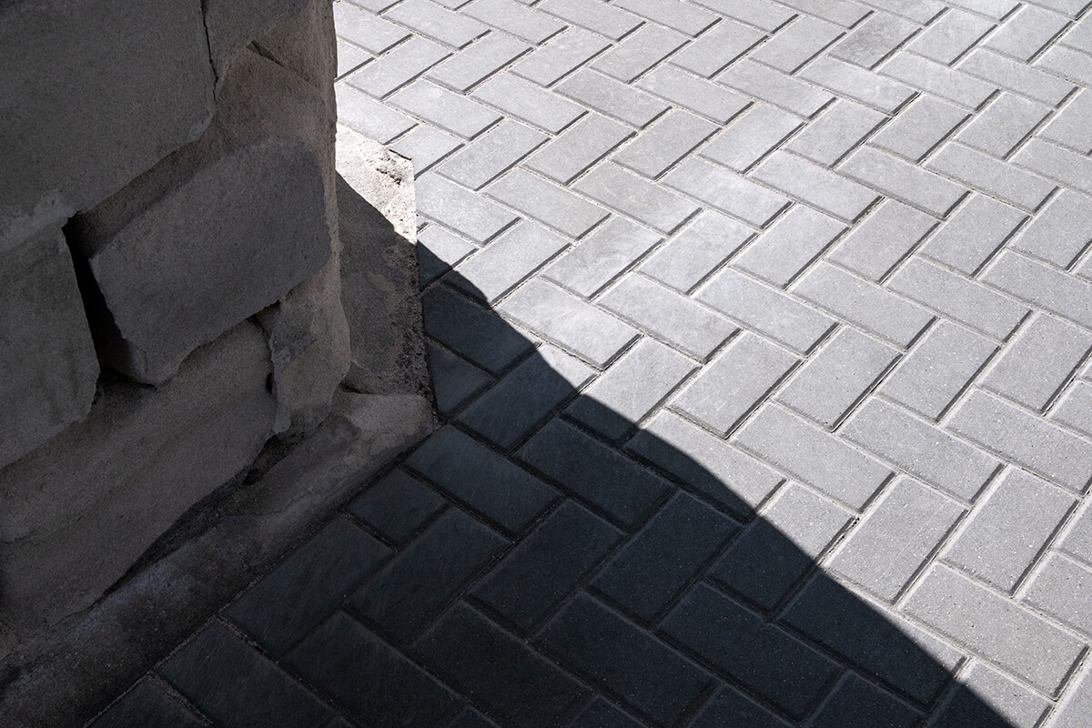 Lifestyle Construction Shadow cast on grey brick pavement from adjacent stone wall, adding a touch of urban elegance perfect for any Toronto renovation. Home Renovation In The GTA